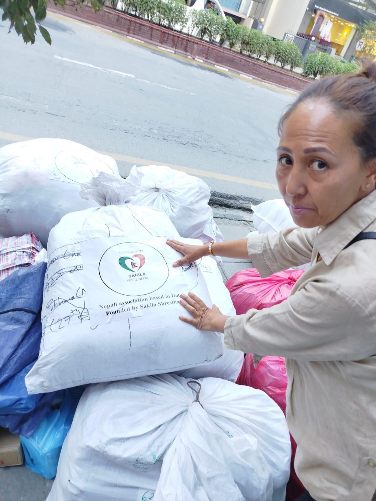 A volunteer beside sacks of aid marked with the association's logo, ready for delivery